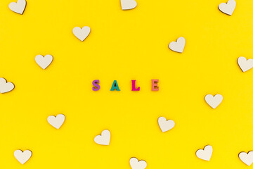 Inscription sale in wooden letters on a yellow background.