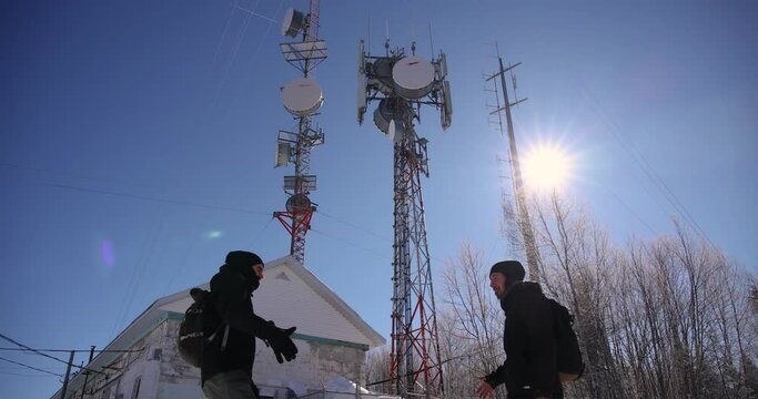 A happy video of two explorers shaking hands and hugging at the base of 4G and 5G telecommunication base tower, located in an isolated area.