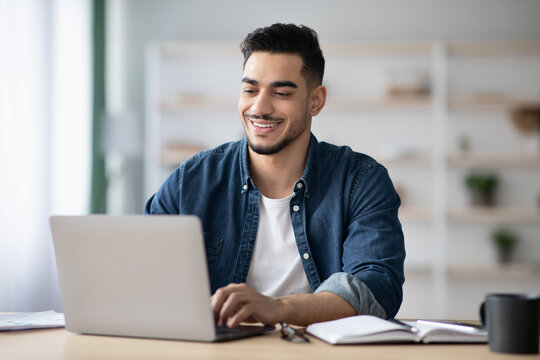 Cheerful Arab Guy Working On Laptop, Typing On Keyboard