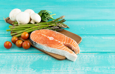 Raw salmon slice with vegetable decoration on blue background. Copy space.