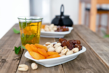 Dried fruit tray with tea glass on wooden background. Copy space.