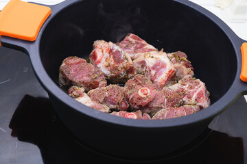 Raw meat ready to be cooked in a black casserole. Cooking concept.