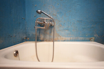 Old vintage dirty water tap in broken bathroom. Trash repairs. Grunge wall background.
