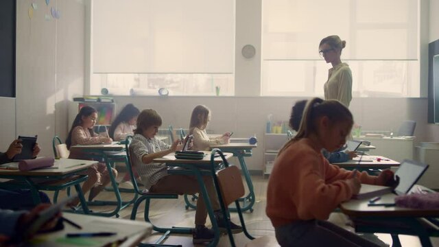 Multi ethnic boys and girls doing online test with digital tablets in classroom