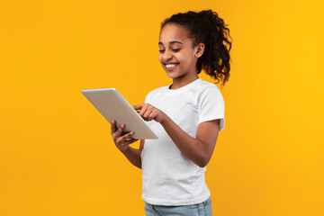 Black girl standing with tablet at yellow studio - Powered by Adobe