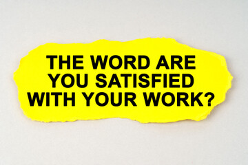 On a white background lies yellow paper with the inscription - THE WORD ARE YOU SATISFIED WITH YOUR WORK