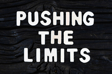 Fototapeta na wymiar Pushing The Limits words on dark wooden background. Business, motivational and inspirational concept.