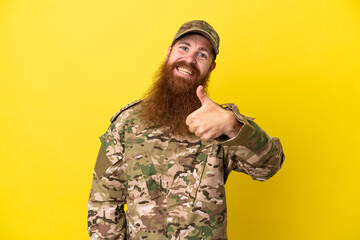 Military Redhead man over isolated on yellow background giving a thumbs up gesture