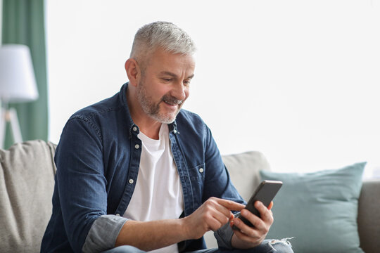 Smiling Senior Man Using Smartphone At Home