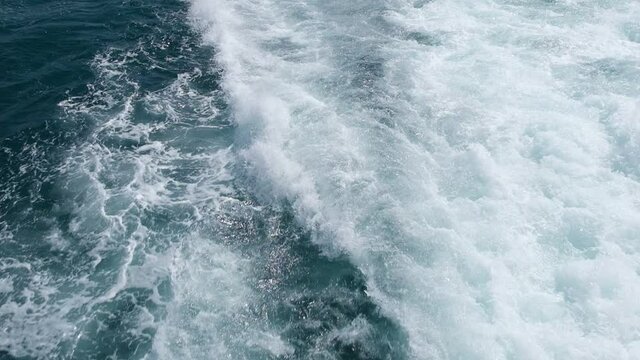 Wake and splashing waters of a motorboat from high angle view in super slow motion
