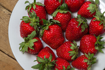 Strawberries in a plate on a wooden table. Ripe fresh strawberries. Healthy diet.