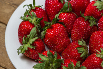 Strawberries in a plate on a wooden table. Ripe fresh strawberries. Healthy diet.