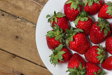 Strawberries in a plate on a wooden table. Ripe fresh strawberries. Healthy diet.
