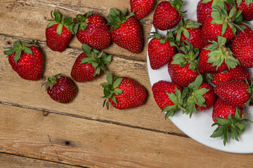 Strawberries in a plate on a wooden table. Ripe fresh strawberries. Healthy diet.