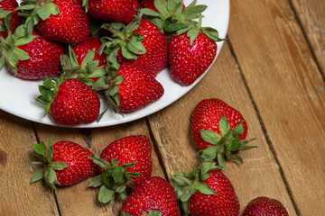 Strawberries in a plate on a wooden table. Ripe fresh strawberries. Healthy diet.