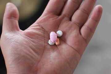 close up of asian man's hand holding some pills