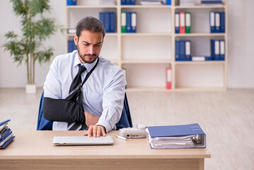 Young arm injured male employee working in the office