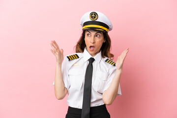 Airplane middle aged pilot woman isolated on pink background with surprise facial expression