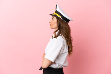 Airplane middle aged pilot woman isolated on pink background in lateral position - obrazy, fototapety, plakaty