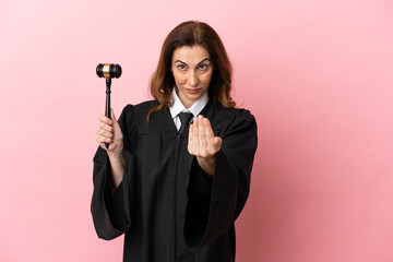 Middle aged judge woman isolated on pink background inviting to come with hand. Happy that you came