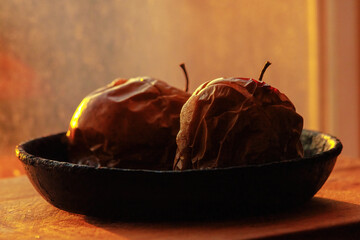 Baked apples in a frying pan, on a wooden stand.