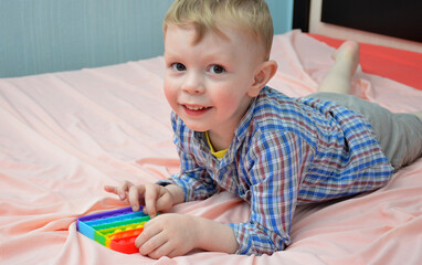 Little boy plays with a toy. POP IT