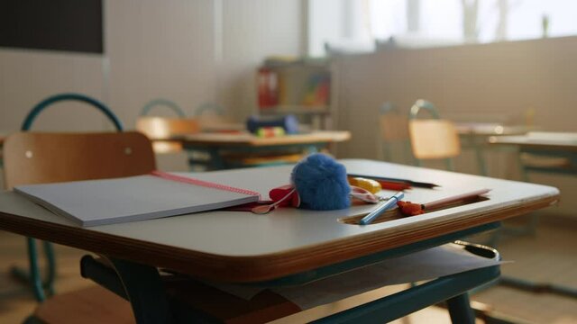 Notebook and pencils lying on desk in classroom. Table with school supplies