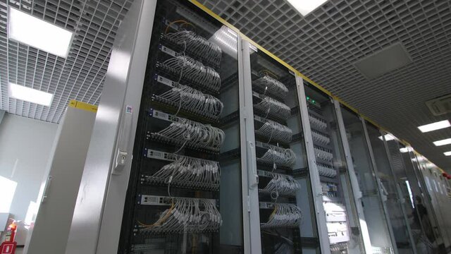 Cabinets with glass doors and connected wires in modern electricity production substation control premises close view