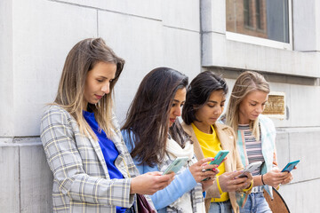 Group of beautiful young female friends of different race using smart mobile phones app, Teenagers addiction to new technology trends, showing Concept of youth, tech, social and friendship, Focus on