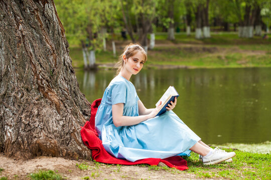 Young beautiful girl reading a book in a summer park
