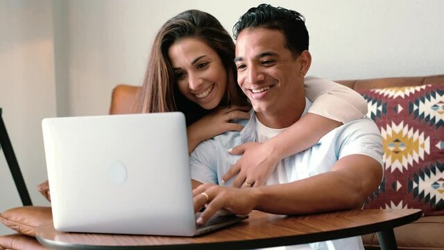 Close up of young couple working on laptop at home - happy people enjoy online computer and connection together with fun and happiness - love and life - interracial relationship man and woman