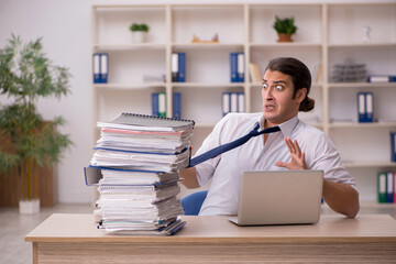Fototapeta premium Young male employee and a lot of work in the office