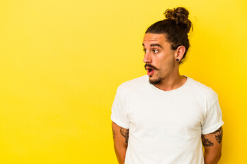 Young caucasian man with long hair isolated on yellow background being shocked because of something she has seen.