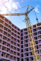 Fototapeta na wymiar Tall building under construction with scaffolds,Freestanding tower crane on a building site.Building construction site work against blue sky