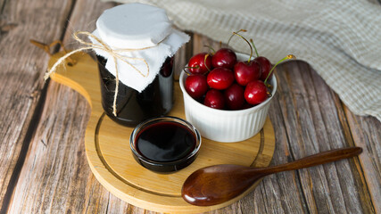 Cherry jam and fresh cherries on wooden background