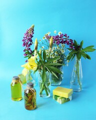 A bouquet of useful herbs and flowers, natural soap, aromatic oil on a bright background