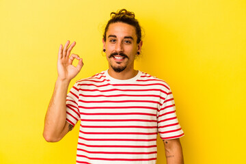 Young caucasian man with long hair isolated on yellow background cheerful and confident showing ok...