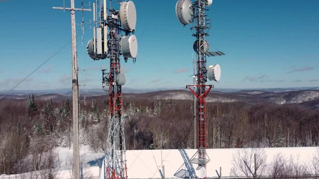 Full look at the state of art modern 4G and 5G telecommunication towers on hill top, with various satellites and antennas attached to them