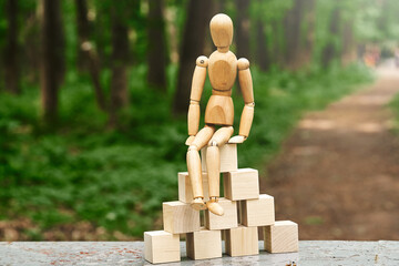 pyramid made from wooden toy blocks and wooden man on nature background