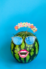 Comic stylish watermelon with lips in sunglasses on a blue background. Festive minimalism concept of summer fruits. Vertical position. Copy space