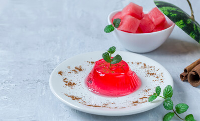 Jelly with mint and cinnamon on a white plate on a light background. Homemade watermelon dessert. Copy space.