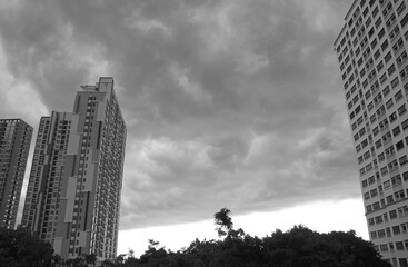 Incredible dark gray nimbus clouds over skyscrapers before the heavy rain in monochrome