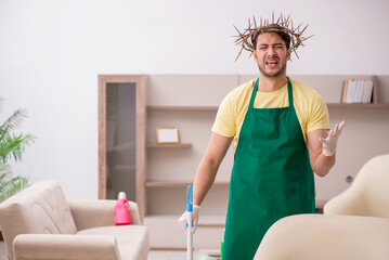 Young male contractor wearing prickly wreath on head cleaning th