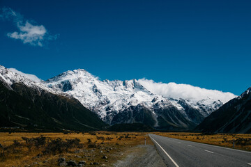 A Snowy Mountain In Front Of A Long Road