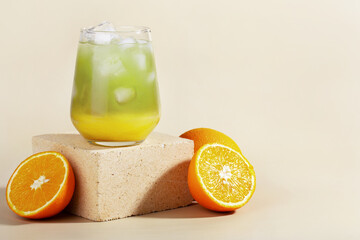 Obraz na płótnie Canvas matcha tea with orange juice and ice in a glass, summer cocktail, healthy drink, hard light