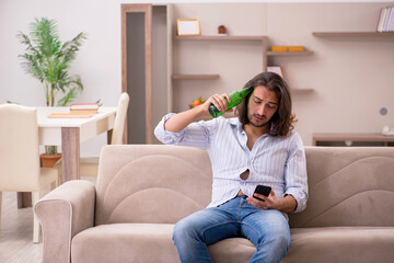 Young man drinking alcohol at home