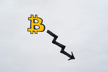 Yellow Bitcoin symbol with black arrow going down. Negative trends in bitcoin exchange rates, down trend.