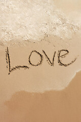Love Romance during summer holidays on the sea. Inscription Love drawn on the sand. Concept of warm feelings, love and friendship, vertical image.