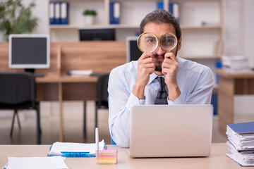Young businessman employee holding loupe in auditing concept