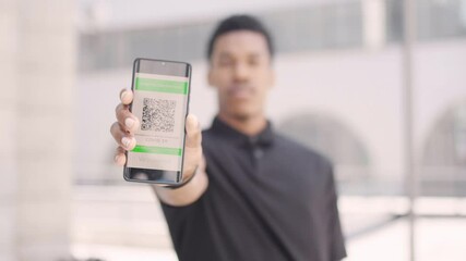 Young African American man showing his digital green pass. Certificate of immunity as proof of vaccination against covid 19. Ready to travel concept. - Powered by Adobe